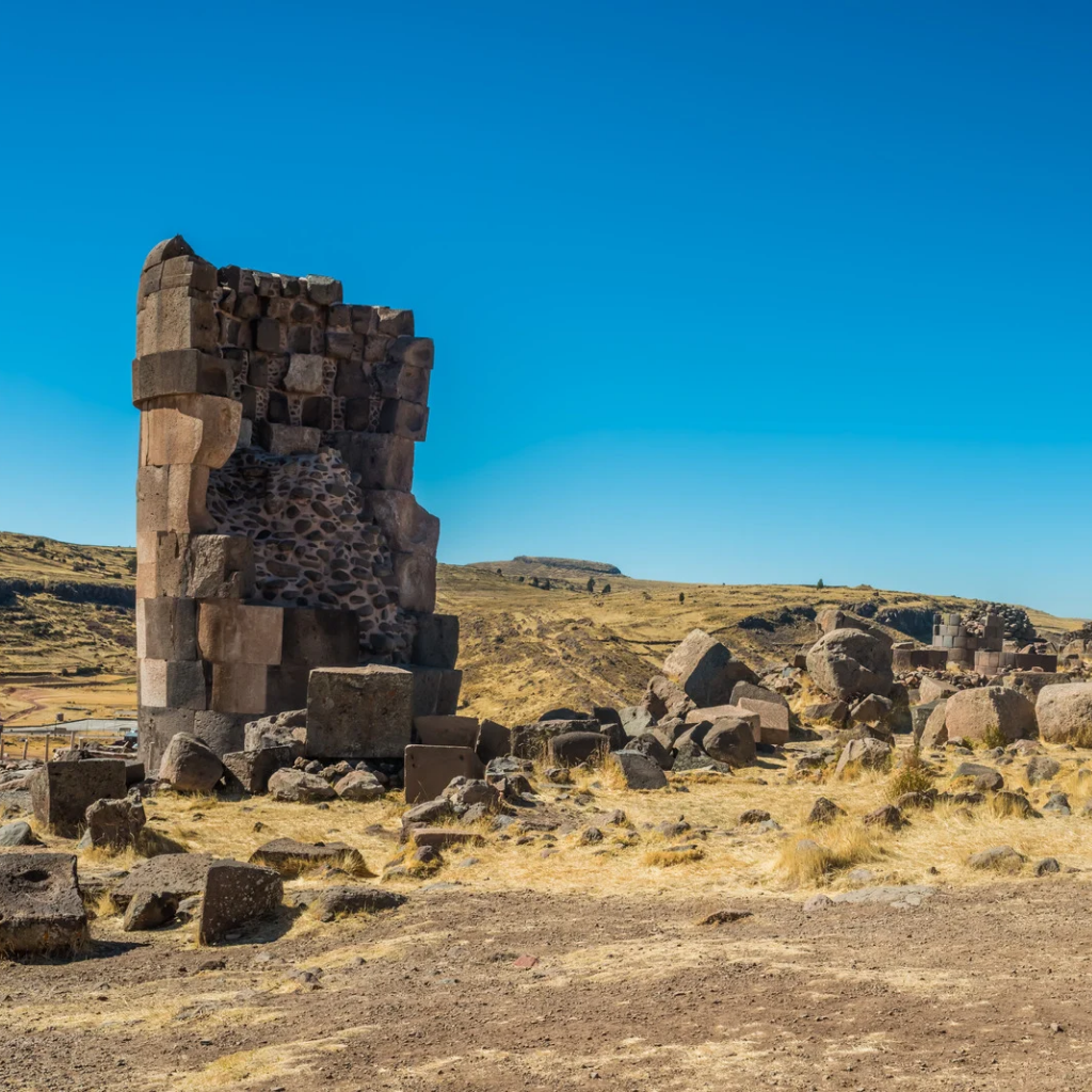 Restos arqueológicos de una chullpa de piedra destruida en Sillustani, mostrando su estructura interna y bloques de piedra esparcidos en Puno
