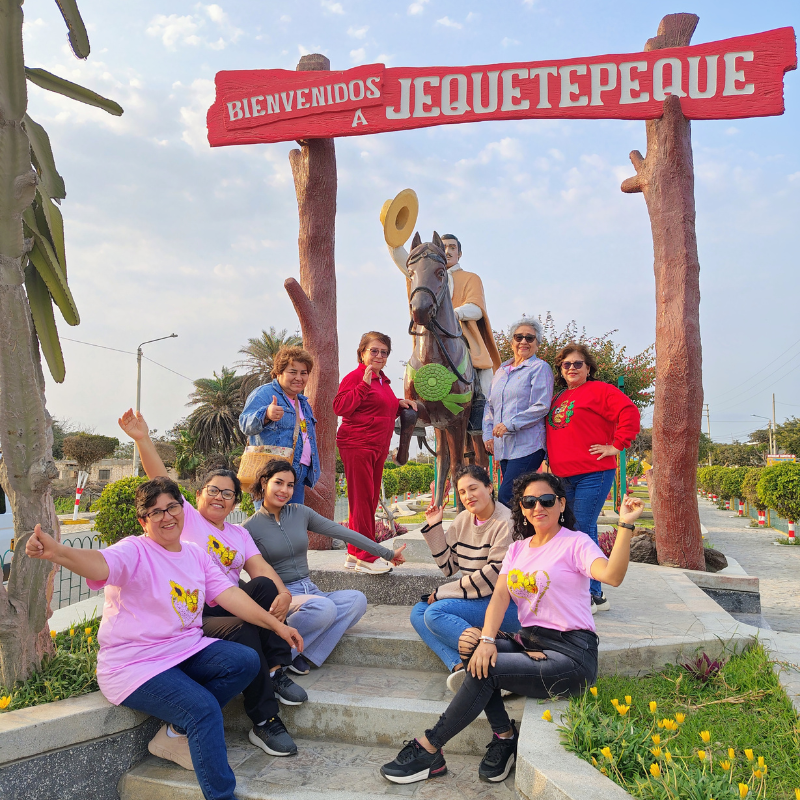 Grupo de turistas posando junto al monumento del chalán a caballo bajo el letrero de Bienvenidos a Jequetepeque en Pacasmayo