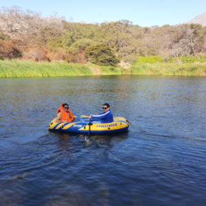 Pareja de turistas navegando en un bote inflable Intex Challenger sobre una laguna tranquila rodeada de vegetación campestre