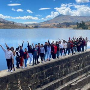 Gran grupo de turistas posando y saludando alineados sobre el borde de piedra del imponente Dique de Carabamba en la ruta Salpo