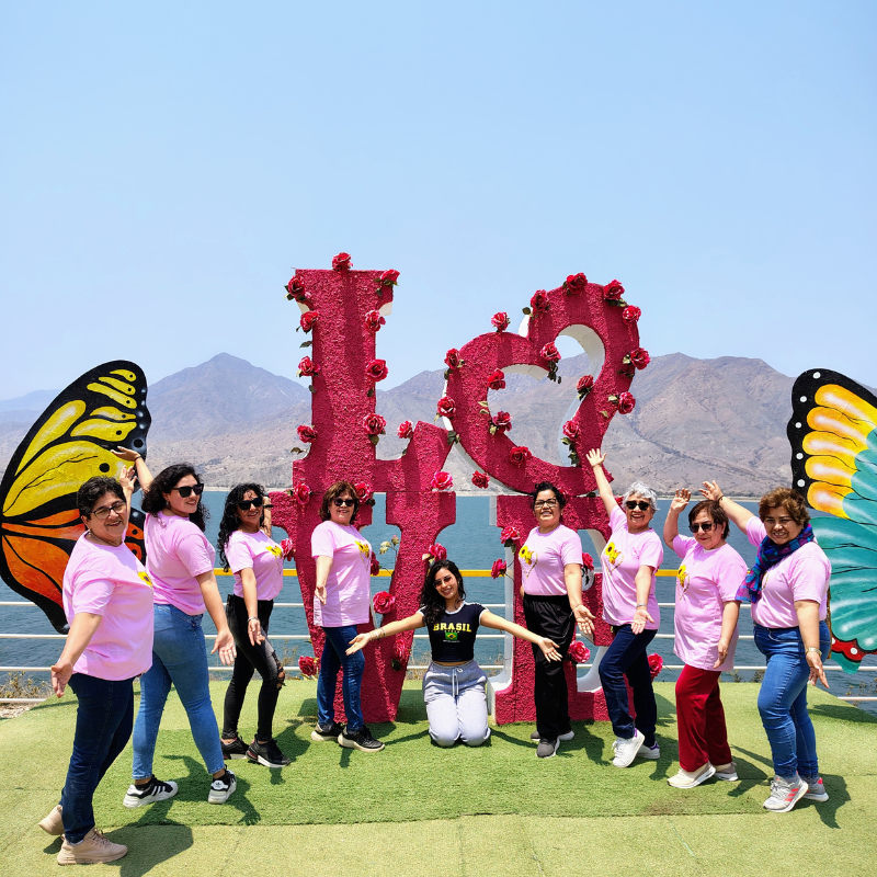 Grupo de turistas con polos rosados posando junto al letrero gigante de LOVE en el mirador de la Represa de Gallito Ciego