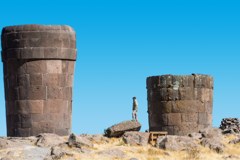 Torres funerarias de piedra en el complejo arqueológico Chullpas de Sillustani junto a un turista, atractivo turístico cultural en Puno, Perú.